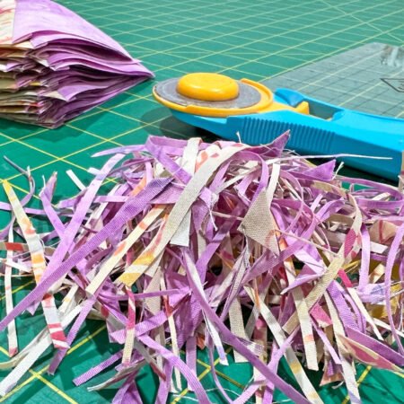 Top US quilting blog and shop, Kate Colleran Designs, shares about new quilts in the new year! Image is of yellow and lavendar scrap fabrics and a rotary cutter from trimming squares