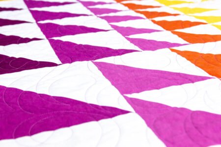 Top US quilting blog and shop, Kate Colleran Designs, shares about new quilts in the new year! Featured quilt is in HST in bright solid yellow, orange, magenta, pink and purples.