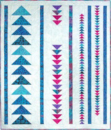 Top US quilting blog and shop, Kate Colleran Designs, shares Summer Twilight batiks and her project in the fabrics! Image is a flying geese quilt in blue, pink and purple batiks