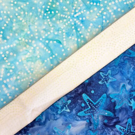 Top US quilting blog and shop, Kate Colleran Designs, shares about the January Quilt Block Remix Challenge and her fabric pull. Image is of 3 batik fabrics in light blue, off-white and dark blue.