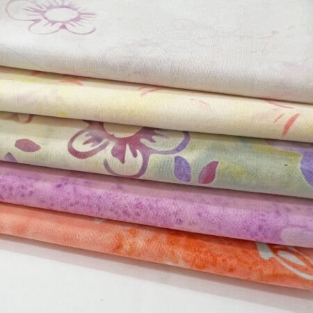 Top US quilting blog and shop, Kate Colleran Designs, shares about her February quilt block fabrics in the remix challenge. Image is a small stack of batiks in white, yellow, green, purple and orange.