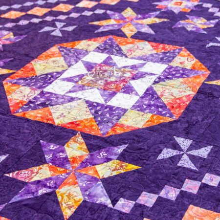 Top US quilting blog and shop, Kate Colleran Designs, shares about her new batik fabric line Winged Things and a FQ giveaway! Image is a quilt - a large star  in the center in purple, oranges and yellow batiks.