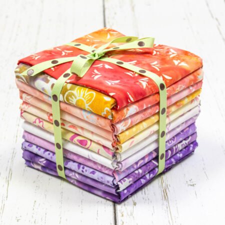 Top US quilting blog and shop, Kate Colleran Designs, shares about her new batik fabric line Winged Things and a FQ giveaway! Image is a stack of orange, yellow, white and purple batik fat quarters.