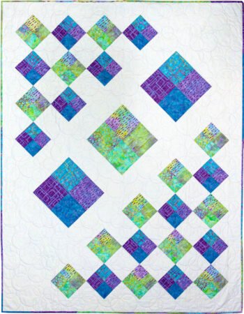 Top US quilting blog and shop, Kate Colleran Designs, shares about a batik line Fairy Floss and her quilt pattern Four Square.  Image is of a quilt made of squares using white, blue, purple and green batiks.