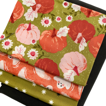 Top US quilting blog and shop, Kate Colleran Designs, shares about her new quilt along called Fall O'Ween! Image is 4 fabrics in a pile- green with pumpkins, orange with ghosts, green with stars and a solid black.
