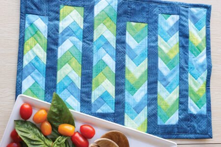 Top US quilting blog and shop, Kate Colleran Designs, shares about her new quilt book called Patchwork Braids and her pre-sale! Image is blue and green braid placemat with a tray of fresh veggies.