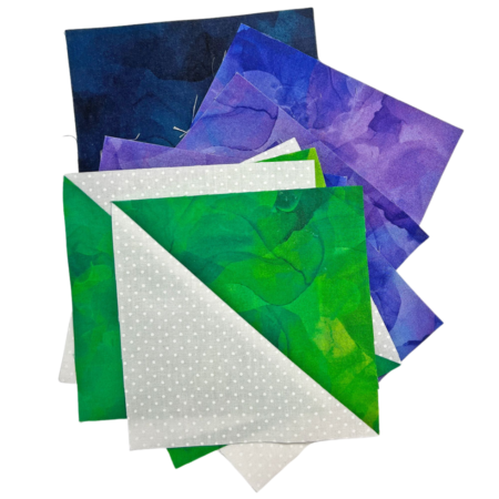 Top US quilting blog and shop, Kate Colleran Designs, shares about the Allure BOM quilt Block 6 and tips! Image is a green and white pieced HST units and a stack of purple and deep blue fabric squares.