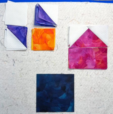 Top US quilting blog and shop, Kate Colleran Designs, shares tips in the Allure BOM Block 7 post. Image is of white and purple HST units, magenta pink FG units, pink rectangle, deep blue square and small white and orange square laid out to create a quilt block.