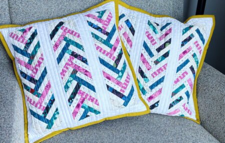 Top US quilting blog and shop, Kate Colleran Designs, shares about her book Patchwork Braids and using pieced strips in a braid. Image is 2 pillows with pink and blue fabric braids with white. 