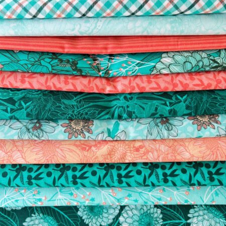 Top US quilting blog and shop, Kate Colleran Designs, shares about her new Chalk Hill Blue quilt pattern! Image is a bunch of fabrics in teal, white and orange.
