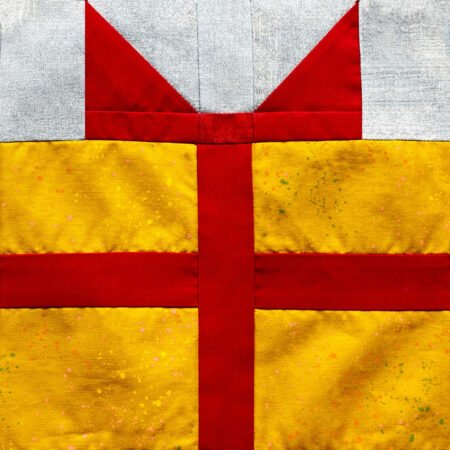 Top US quilting blog and shop, Kate Colleran Designs, shares about Block 4 Gifts Galore in the Jingle Bell Pines BOM Block Party! Image is a gift quilt block in red, yellow and pale blue.