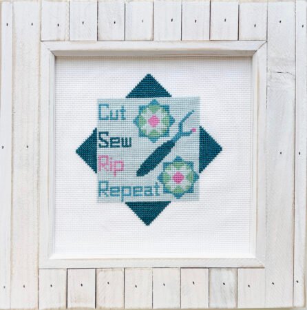 Top US quilting blog and shop, Kate Colleran Designs, shares about her Christmas in July posts and a last giveaway for the month! Image is a cross stitch pattern that says Cut, Sew, Rip, Repeat. Shown in blues, teals, pink and green in a white wooden frame.