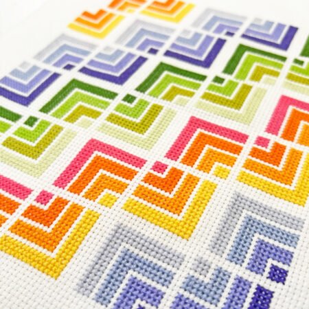 Top US quilting blog and shop, Kate Colleran Designs, shares about her Christmas in July posts and a last giveaway for the month! Image is a cross stitch pattern in oranges, purples and greens featuring log cabin quilt blocks.