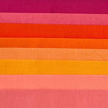 Top US quilting blog and shop, Kate Colleran Designs, shares about a quilt from Patchwork Braids and tips on recoloring a quilt. Image is a flat shot of a orange, red and gold solid fabrics.