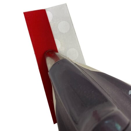 Top US quilting blog and shop, Kate Colleran Designs, shares about the Jingle Bell Pines BOM Block Party Block 5 Jingle Socks! Image is a red and white strips set with the tip of the iron pressing the seam on the front of the strip set.