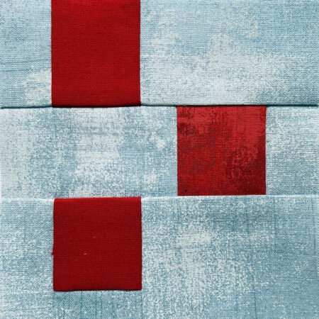 Top US quilting blog and shop, Kate Colleran Designs, shares about the Jingle Bell Pines BOM Block Party setting blocks and borders. Image is a quilt block of squares and rectangles in red and light blue to represent berries.