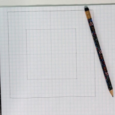 Top US quilting blog and shop, Kate Colleran Designs, shares about new projects using quilt blocks and how to resize. Image is graph paper and pencil showing a block and center lines.
