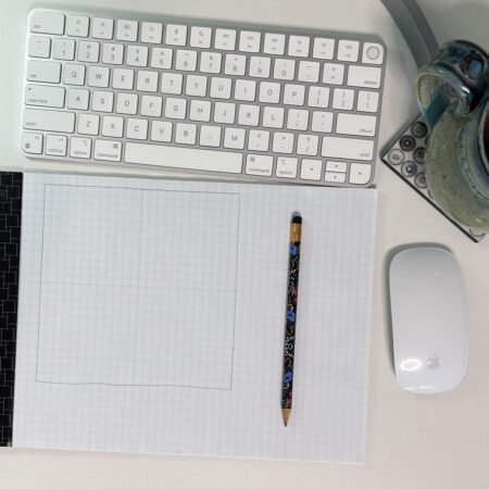 Top US quilting blog and shop, Kate Colleran Designs, shares about new projects using quilt blocks and how to resize. Image is graph paper and pencil showing showing a block and center lines.