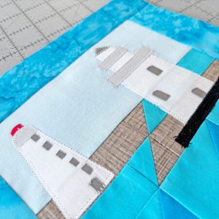 closeup of appliqué lighthouse quilt block showing stitching around the white lighthouse shapes