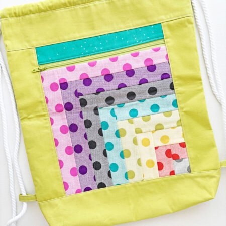 a backpack with a log cabin quit blocks and outside zippered pocket 