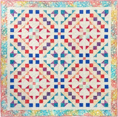 Starbound quilt in Groovy batiks in blues, creams, red, orange, aqua and purple with HST units and chains of squares criss crossing the quilt and a floral border